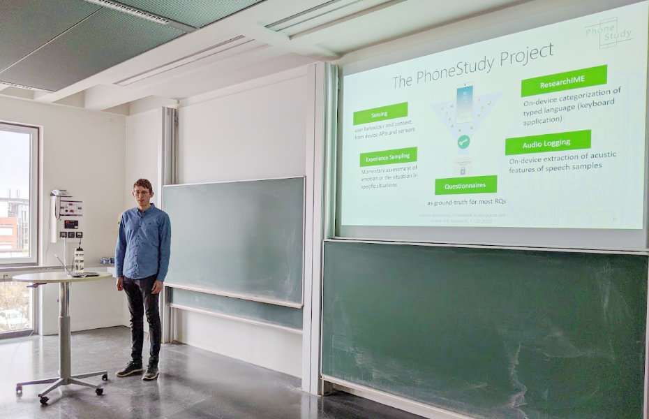 Florian Bemmann during his talk, in front of the seminar room next to his slides on the projector